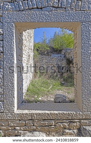 View through a window opening in an antique natural stone wall during the day