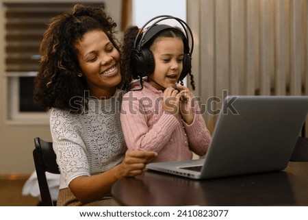 Happiness mother and daughter use laptop and headphone for entertain , family joyful together in the house.