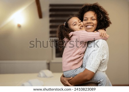 Portrait of happy mother and daughter hugging each other in bedroom at home