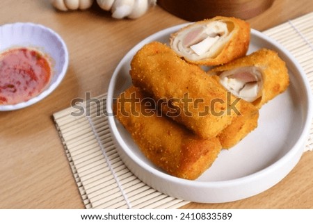 kue risoles mayo (risoles mayo cake) on wooden tray and penaut sauce served on table top. risoles mayo cake is one of popular indonesian foods. Royalty-Free Stock Photo #2410833589