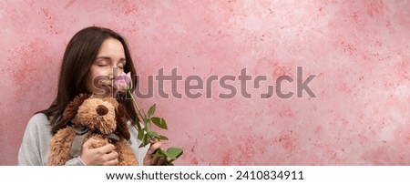 Woman holding rose and stuffed animal toy gift. Pink background. Banner with copy space.