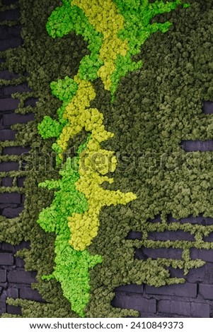 Moss. Black brick wall with green artificial moss. Background with place for text. Vintage and retro backdrop. Picture for adding text message. The backdrop for design artwork. Details closeup.