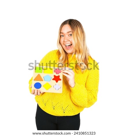 Excited young blonde female teacher holding a kids toy against a white background