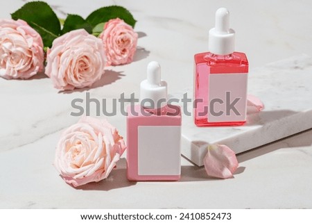 anti-aging rose collagen facial serum in square glass bottles on white marble background with copy space. Natural Organic Cosmetic Beauty Concept. Mockup for branding