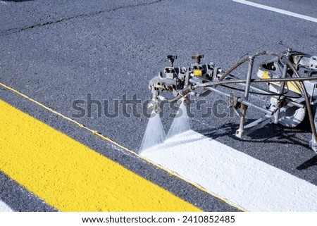 a team of workers drawing a pedestrian crossing in early spring using automated equipment on fresh asphalt Royalty-Free Stock Photo #2410852485