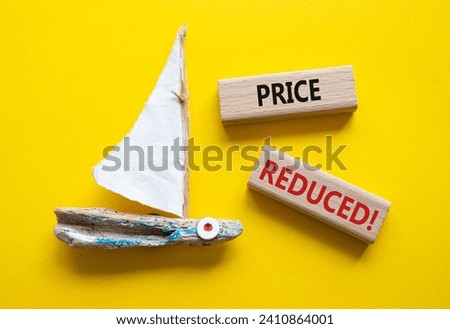 Price reduced symbol. Concept word Price reduced on wooden blocks. Beautiful yellow background with boat. Business and Price reduced concept. Copy space