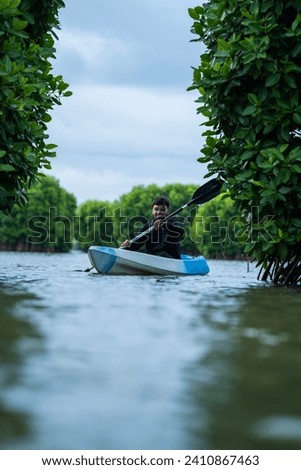 Kayaking through mangrove forest, man canoeing on the lake with beautiful nature view, Kerala water adventure activity image from Kavvayi Island Kannur Royalty-Free Stock Photo #2410867463