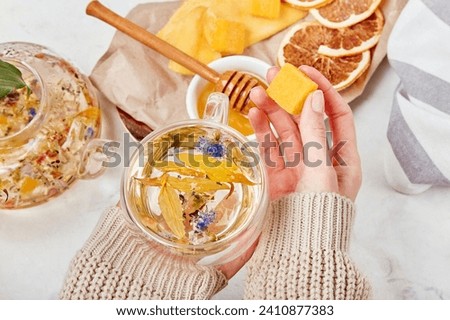Woman add honey to organic mountain blend - calming herbal elixir -wellness retreat with herbal infusions. Royalty-Free Stock Photo #2410877383