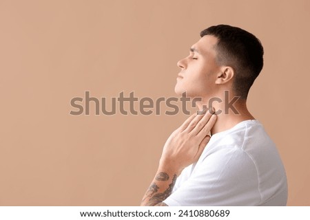 Young man with thyroid gland problem on beige background