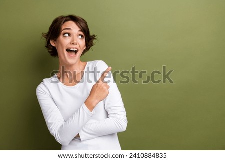 Portrait of excited charming girl direct finger empty space sale offer shop store mall season isolated khaki green color background