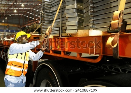 African American male worker driving steel trailer inspecting the safety system checking condition belt tightening safety material before traveling for ready travel deliver goods and prevent accident.