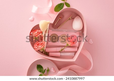 Unwrap romance with heart-shaped box filled with beauty essentials: lip gloss, cosmetic brushes, eyeshadow palette, mascara, beauty blender, and more. Top view on soft pink backdrop adorned with roses Royalty-Free Stock Photo #2410887997