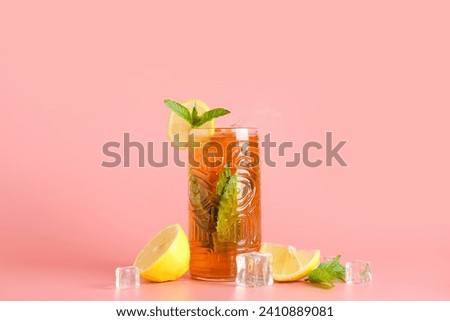 Glass of ice tea with splashes on pink background
