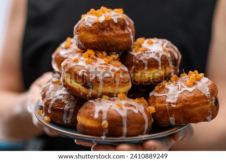A stack of donuts for Fat Thursday with jam, icing and orange peel Royalty-Free Stock Photo #2410889249