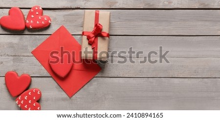 Tasty heart shaped cookies with envelope and gift on grey wooden background with space for text. Valentine's Day celebration