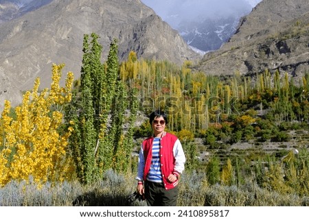 An Asian female tourist admiring the view of the beautiful foliage with leaves changing colors in Hunza Valley in Gilgit-Baltistan, Pakistan.