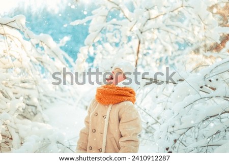 Boy catches snowflakes with his mouth in a winter snowy forest. Frosty sunny day.