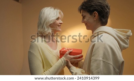 Happy man giving gift to his girlfriend on beige studio background, free space.
