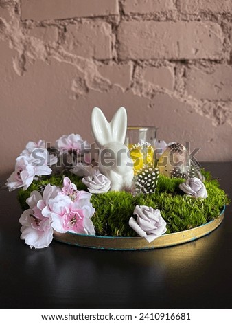 Photo with Easter composition and candle. Spring mood. The composition consists of a porcelain bunny, candle feathers and green moss. A beautiful holiday card.