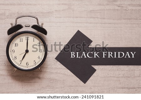 alarm clock showing seven with arrow sign indicating black friday
