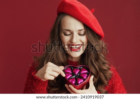 Happy Valentine. happy stylish female in red sweater and beret with heart shaped candy box.