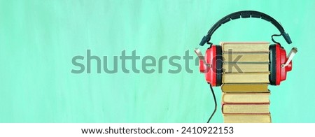Relaxing with audiobooks concept with heap of books and vintage headphones.Bright green background with large copy space