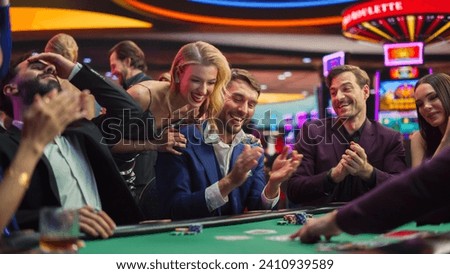 Intense Win in a Poker Game on a Casino Floor Championship. Handsome Man Has Stronger Hand and Beats Opponents with His Card Deal. Triumphant WInner Shaking Hands and Celebrating Royalty-Free Stock Photo #2410939589