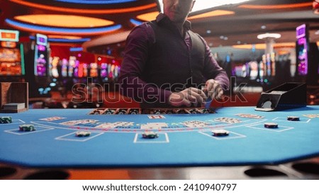 Casino Card Game Table: Professional Dealer Running a Blackjack Game. Anonymous Male Croupier Dealing Playing Cards for Placed Bets. Betting on Payout, Strategy and Luck. Cinematic Shot Royalty-Free Stock Photo #2410940797