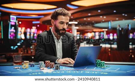 Portrait of a Young Man on Casino Floor, Using Laptop Computer to Play Online Casino Betting Jackpot Games. Professional Businessman Focused on Winning Jackpot Bet. Luck and Strategy Royalty-Free Stock Photo #2410940811