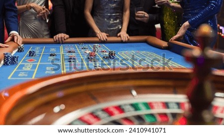 Successful Men and Women Partying in a Luxurious Casino. Young Anonymous People Gambling at a Roulette Table, Putting High Stakes Bets. Entertainment Industry and Glamorous Lifestyle Concept Royalty-Free Stock Photo #2410941071