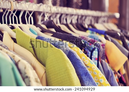 some used clothes hanging on a rack in a flea market Royalty-Free Stock Photo #241094929
