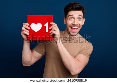 Photo of cheerful funky man in stylish clothes hand showing red heart card popularity social media isolated on dark blue color background