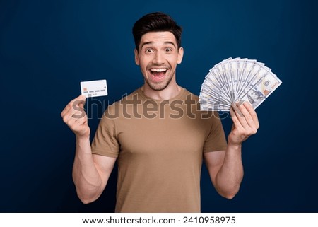 Photo of cheerful excited glad rich man wear trendy clothes showing jackpot banknotes credit card isolated on dark blue color background