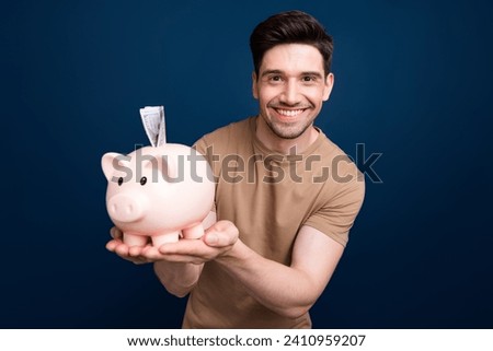 Photo of attractive rich man wear stylish clothes hands showing piggy bank box bank credit storage isolated on dark blue color background