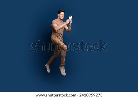 Full size photo of smart clever man dressed beige t-shirt running shopping with smartphone in hands isolated on blue color background