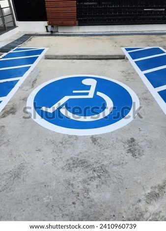 Handicapped symbol white on blue square frame and speed bump on a concrete road. Blue rectangle handicapped sign with wheelchair and orange traffic cone. To create convenience. Parking for wheelchair 