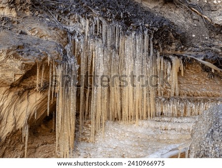 photo of sandstone cliffs, bare ice, sand, roots and ice formations