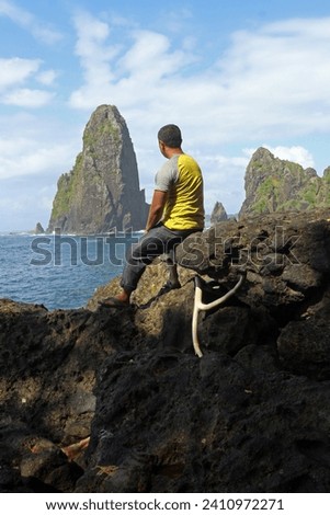 A man sitting on the rocks look away to the sea with rocky islets