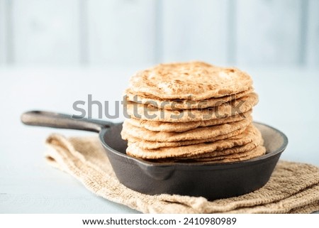 Homemade Indian Traditional Flatbread called Chapati on a white wooden background. Baked indian flatbread. Royalty-Free Stock Photo #2410980989