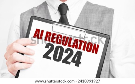 AI REGULATION 2024 inscription on a notebook in the hands of a businessman on a gray background, a man points with a finger to the text