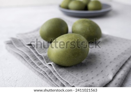 Green eggs on a gray towel on a light background. Minimal concept. View from above. Easter eggs. Photos of preparations for Easter.