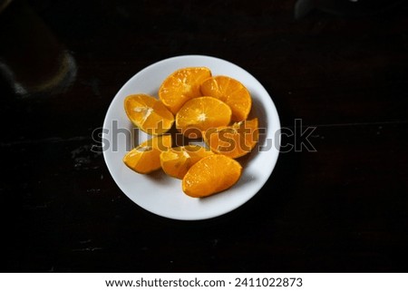 white plate filled with cut orange slices ready to make orange juice with citrous Royalty-Free Stock Photo #2411022873