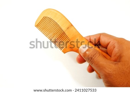 wooden comp holding hand on white background, hand holding comb close up view, eco friendly product display concept  Royalty-Free Stock Photo #2411027533