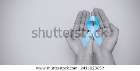 Hand holding blue prostate cancer awareness ribbon with copy space