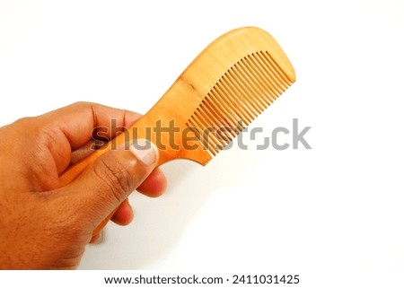 a wooden comb holding hand on white background close-up view single object, hand holding comb isolated on white, eco friendly no wastage product showing concept  Royalty-Free Stock Photo #2411031425