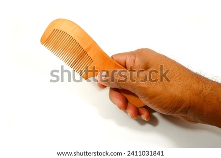 a wooden comb holding hand on white background close-up view single object, hand holding comb isolated on white, eco friendly no wastage product showing concept  Royalty-Free Stock Photo #2411031841