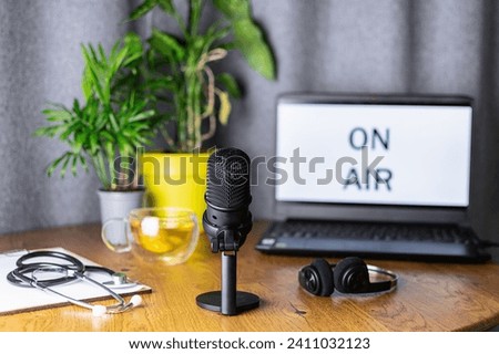 Home podcast office with headphones, laptop, medical stethoscope and microphone on the table close up. Concept of medical podcast.