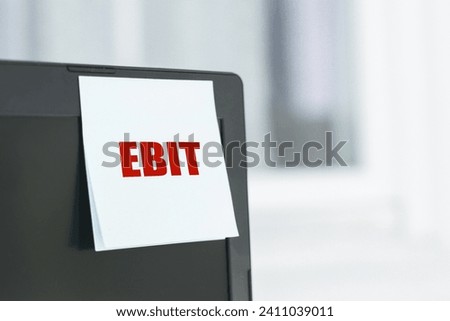 On laptop monitor a white stick note with the inscription - EBIT. Earnings before interest and taxes. Business and finance concept.