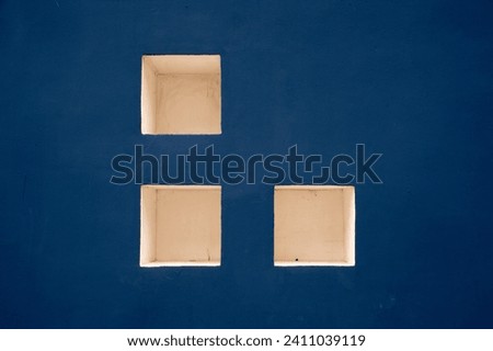 Three white squares on a blue cement wall