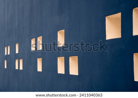 A long blue cement wall with white squares